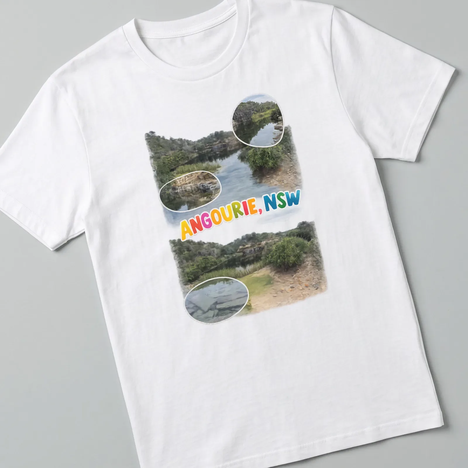 Colorful illustration of a scenic landscape depicting water and rocks with text "ANGOURIE, NSW" — printed on a unisex t-shirt