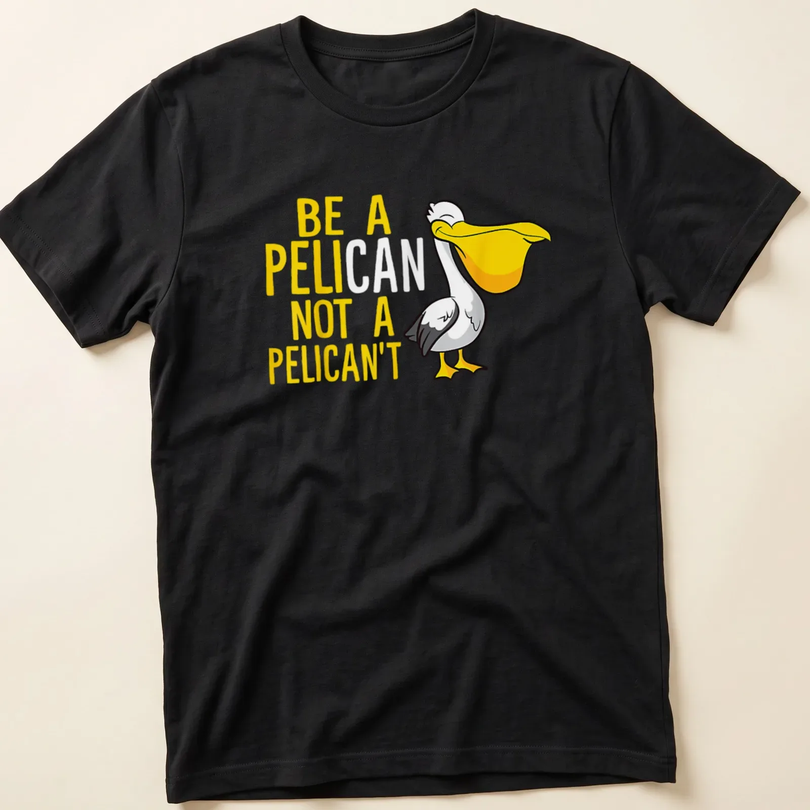 Cartoon pelican graphic with humorous text 'Be A Pelican Not A Pelican't' in yellow, white, and black — printed on a unisex t-shirt