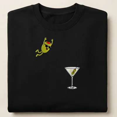 Cartoon olive diving into a dirty martini cocktail, illustrated in green, black, white, and red — printed on a unisex sweatshirt
