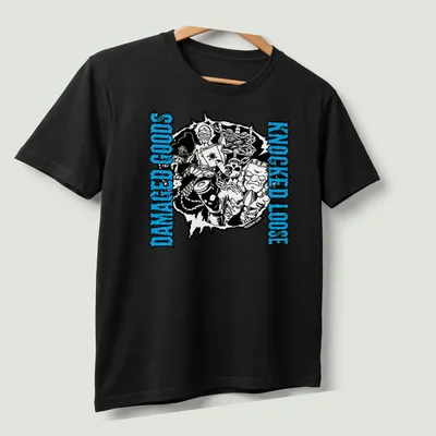 Bold graphic tee with the phrase 'Damaged Goods Knocked Loose' and chaotic illustrated characters in black, blue, and white. — printed on a unisex t-shirt (angled view)