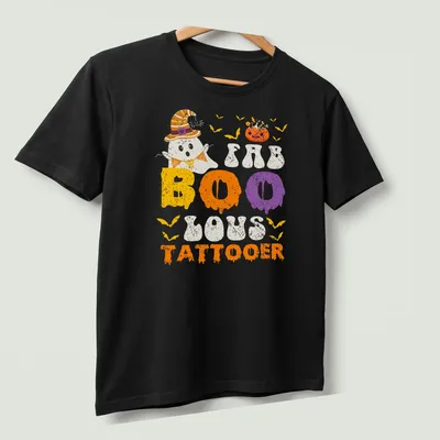 Cartoon ghost with a witch hat and FAB BOO LOUS TATTOOER text in festive colors — printed on a unisex t-shirt (angled view)