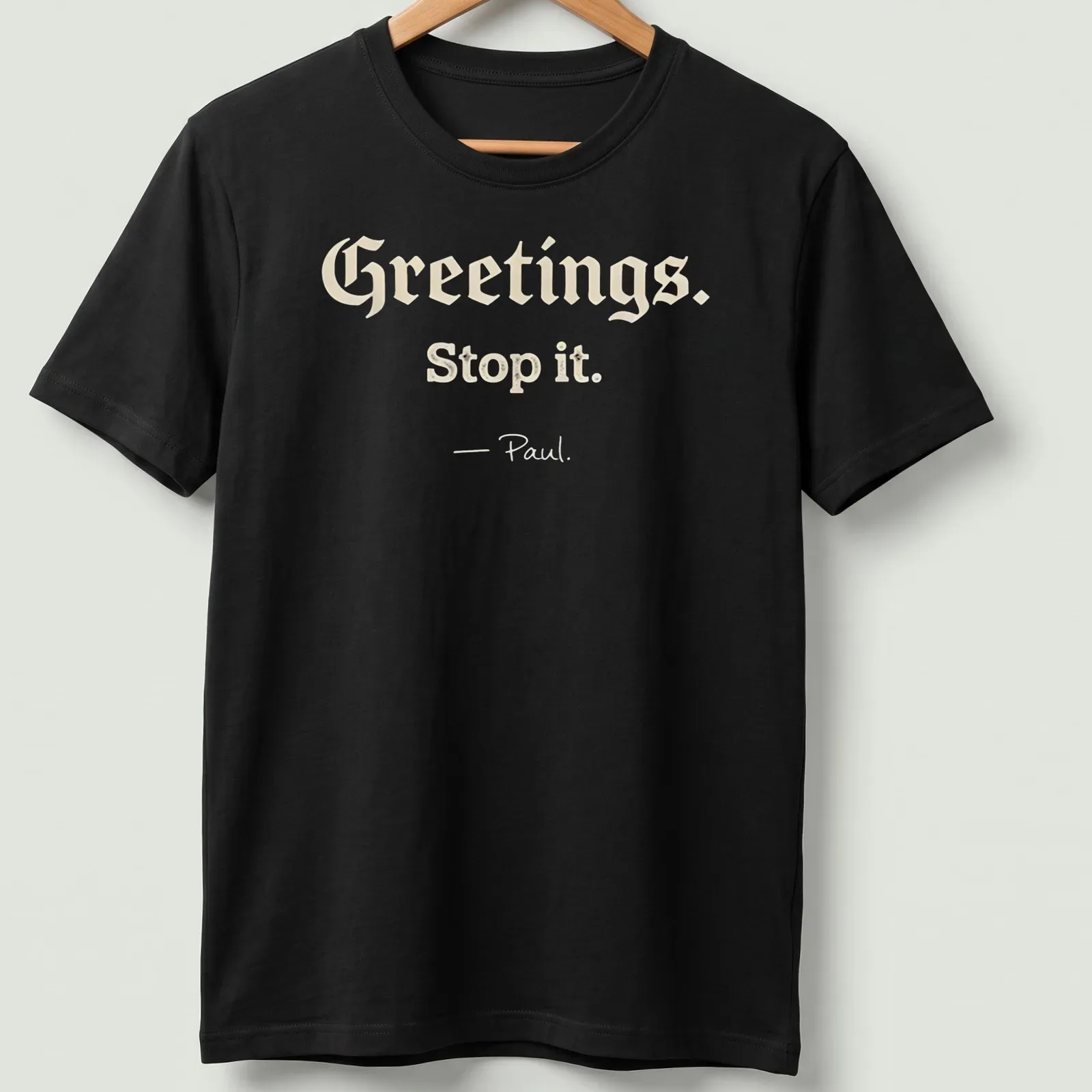 Playful script with Christian humor saying 'Greetings. Stop it. - Paul.' on a cream background — printed on a unisex t-shirt