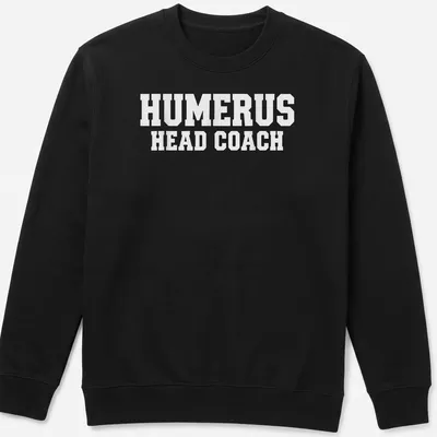 White T-shirt with bold text 'HUMERUS HEAD COACH' and anatomical humerus bone graphic — printed on a unisex sweatshirt