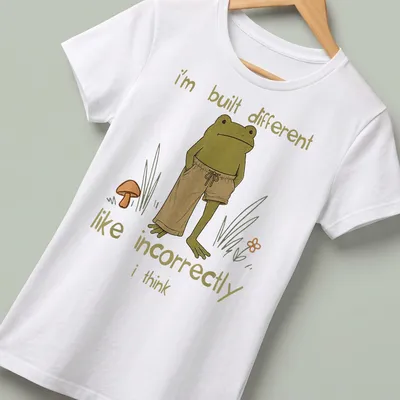 Cartoon frog illustration with humorous text about being different — printed on a women's shirt