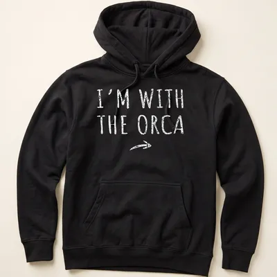 Playful orca-themed shirt with bold text 'I'm With The Orca' for Halloween — printed on a unisex hoodie