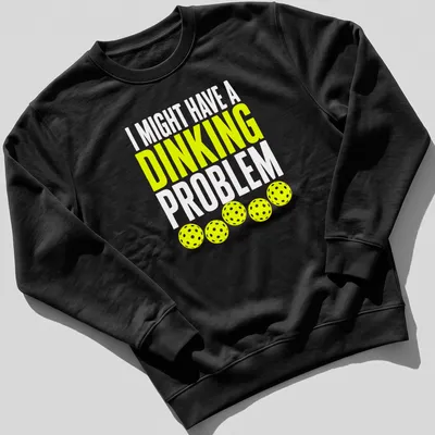 Retro bold text on a shirt saying 'I Might Have A Dinking Problem' with pickleball imagery. — printed on a unisex sweatshirt