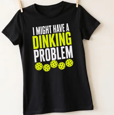Retro bold text on a shirt saying 'I Might Have A Dinking Problem' with pickleball imagery. — printed on a women's shirt