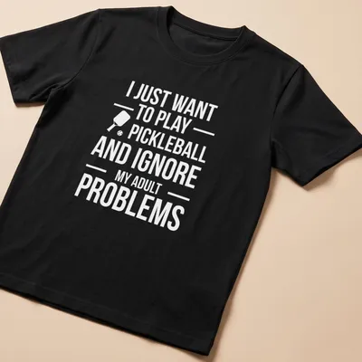 Typography t-shirt with the phrase about ignoring adult problems to play pickleball and a cartoon player
