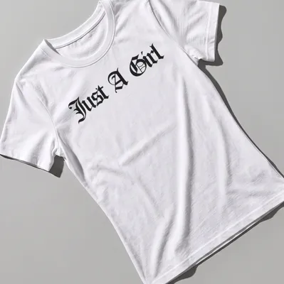 Black gothic lettering on a t-shirt reads Just A Girl — printed on a women's shirt