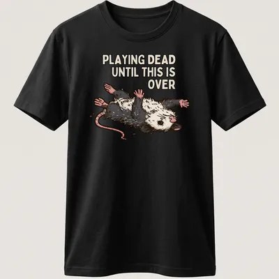 Cartoon opossum with silly expression and text about playing dead during tough times — printed on a unisex t-shirt