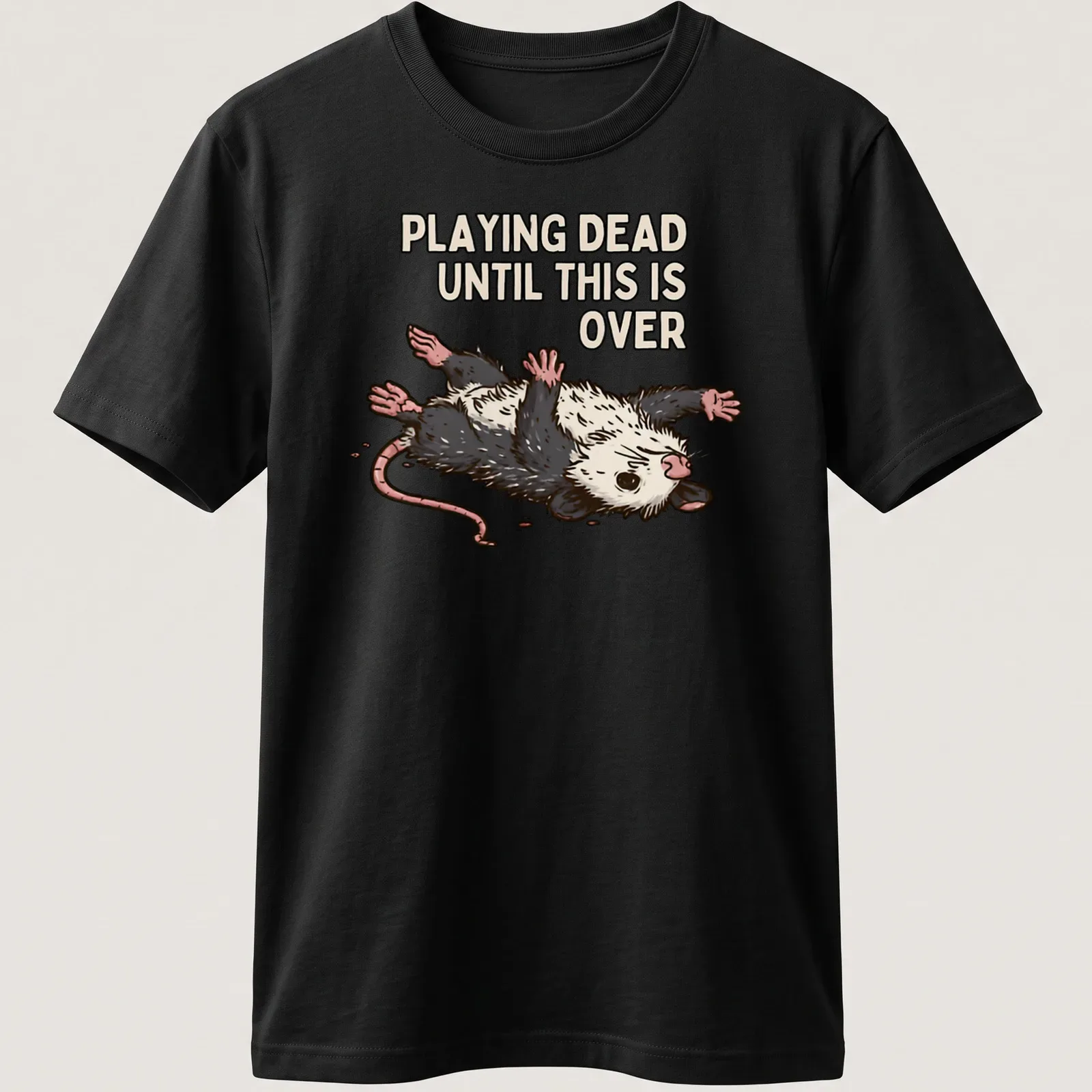Cartoon opossum with silly expression and text about playing dead during tough times — printed on a unisex t-shirt