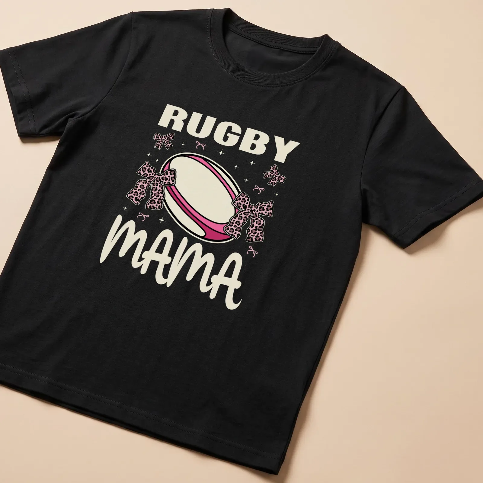 Cute Rugby Mama t-shirt with pink bows and playful rugby ball design — printed on a unisex t-shirt